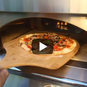 A pizza being taken out of an oven with a wooden peel.