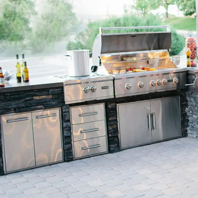 Outdoor kitchen with grill, refrigerator, and storage cabinets.