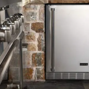 Close-up of a modern stainless steel kitchen appliance next to a brick wall.