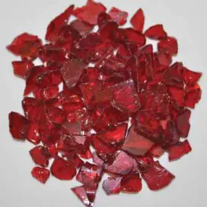 Pile of broken red glass pieces scattered on a white surface.