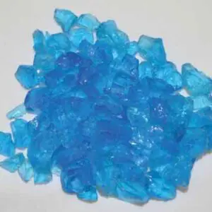 Bright blue crystals scattered on a white surface.