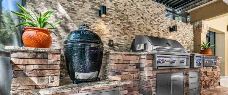 Outdoor kitchen with a kamado grill and brick accents.