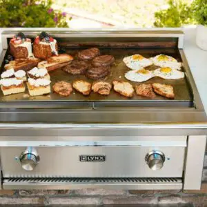 Grilled breakfast with eggs, sausages, and toasted sandwiches on a large outdoor grill.