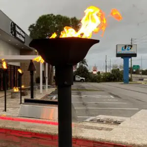 Flaming torch near a parking lot on a cloudy day.